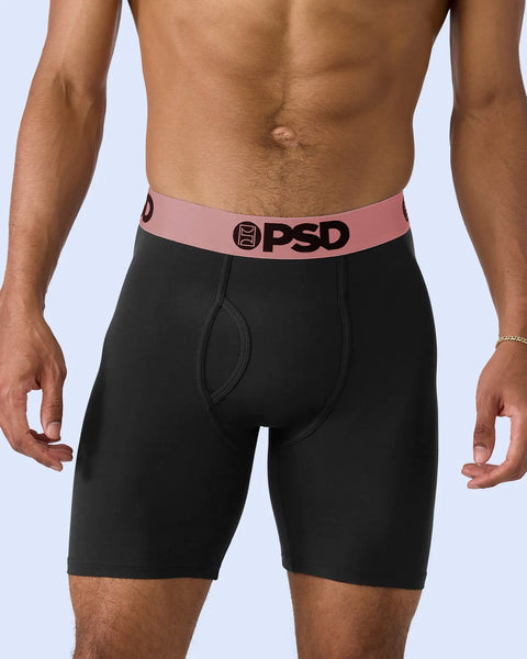 Black boxer briefs with rose gold waistband and PSD logo, worn on male model.