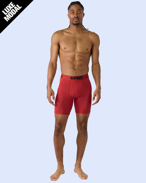 Man wearing red modal shorts with PSD waistband, viewed from front against light blue background.