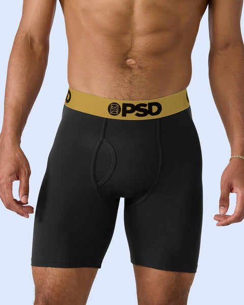 Black boxer briefs with gold and black PSD waistband on model against white background.