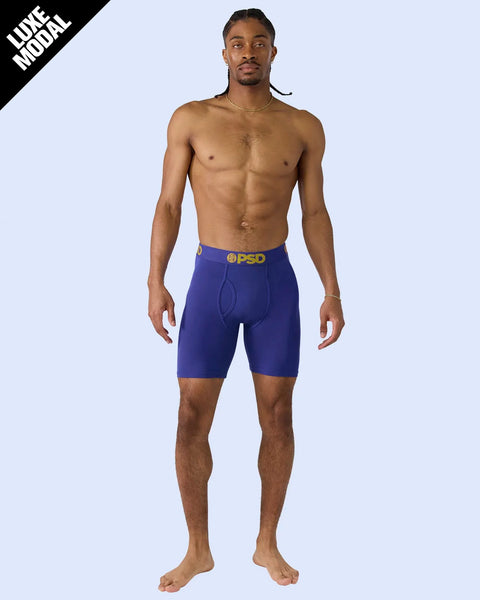 Man wearing royal blue boxer briefs with yellow PSD logo on waistband.