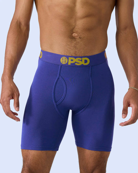 Royal blue boxer briefs with gold PSD waistband and front pouch detail on model.