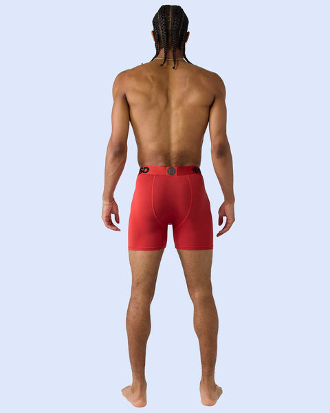 Man wearing red boxer briefs with metallic sheen and metal button detail, shown from behind.