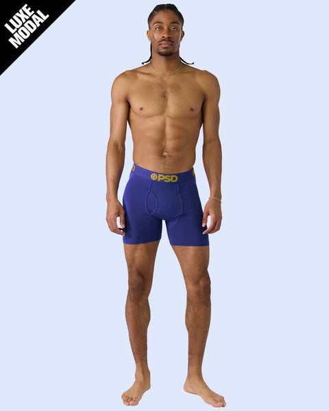 Man wearing royal blue boxer briefs with gold waistband and PSD branding.