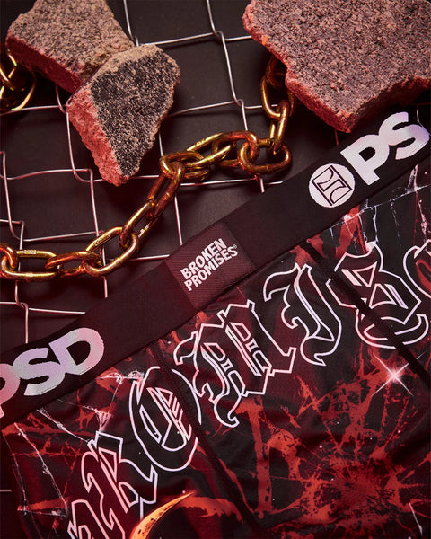 Red and black branded merchandise with gold chain, scattered crumbly textured items, and geometric neon line graphics on dark