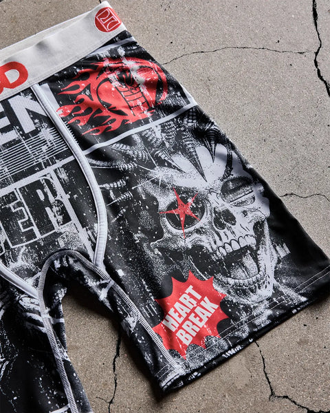 Boxer shorts with white waistband featuring black and white skull graphic with red accents and text design on concrete surfac