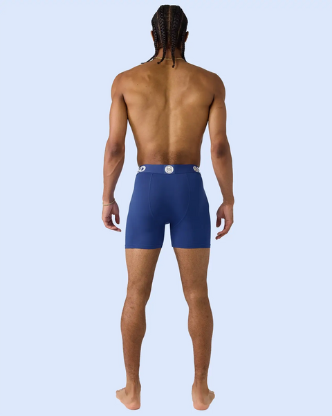 Man wearing navy blue boxer briefs with white waistband logo, shown from behind.