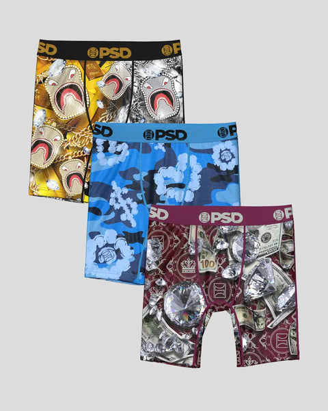 Three PSD boxer briefs with printed patterns: gold with red mouth graphics, blue with cloud camo, and burgundy with dollar bi