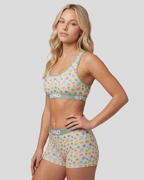 Woman wearing yellow sports bra and shorts with colorful mushroom print and gray PSD waistbands.