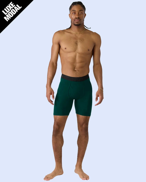 Man wearing deep green modal shorts with black waistband and gold chain necklace.