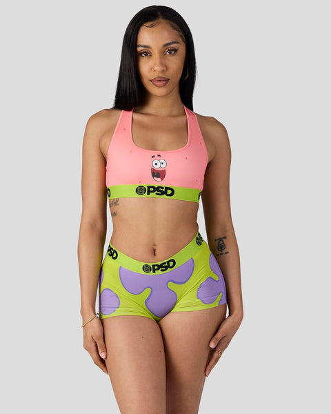 Woman wearing pink sports bra with Patrick face design and lime green shorts with purple starfish pattern.