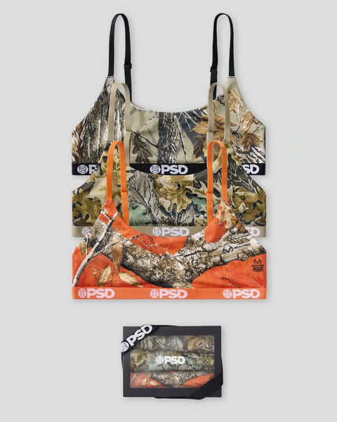 Three sports bras in Realtree camouflage patterns displayed stacked, with packaging box below showing the set contents.