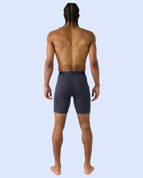 Man wearing dark purple shorts shown from behind against light blue background.