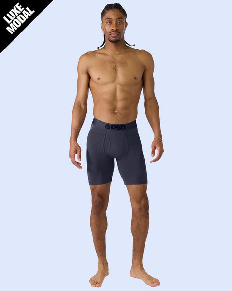 Man wearing dark navy modal shorts with branded waistband against light blue background.